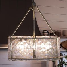 a chandelier hanging from the ceiling in a kitchen with potted plants on the counter