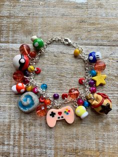 Handmade with polymer clay charms, glass and acrylic beads and silver tone chain. Perfect for the gamer in your life! Currently measures 8 inches, I can add more links if needed. Mushroom Cartoon 90s Kid Controller Video Game CPU AC Money Bag Bell Bag Star Bracelet Mushroom Clay charms made by North Juniper Designs, the other three clay charms (Red & White ball, stone with blue swirl and Bag with star) were made by me. Video Game Polymer Clay, Themed Polymer Clay Jewelry For Gifts, Playful Polymer Clay Bracelet As Gift, Playful Polymer Clay Bracelet For Gift, Multicolor Themed Charm Bracelet As Gift, Themed Multicolor Bracelet Jewelry, Friendship Polymer Clay Bracelet, Multicolor Polymer Clay Bracelet, Handmade Novelty Plastic Jewelry