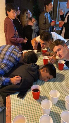 a group of people standing around a table with cups on it