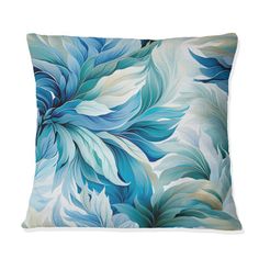 a blue and white pillow with large leaves on the front, sitting on a white surface