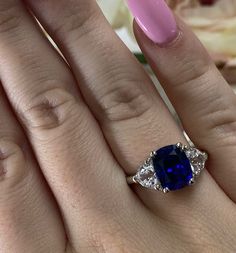 a woman's hand holding a ring with a blue sapphire and diamonds on it