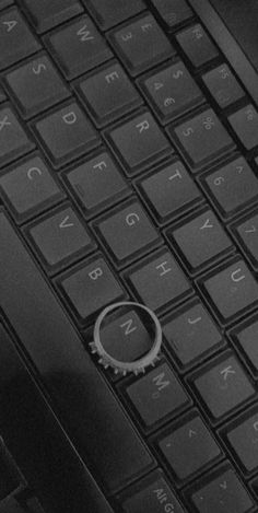 a black and white photo of a computer keyboard with a ring on it's side