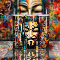 two tumblers with faces painted on them in front of graffiti covered walls and floor