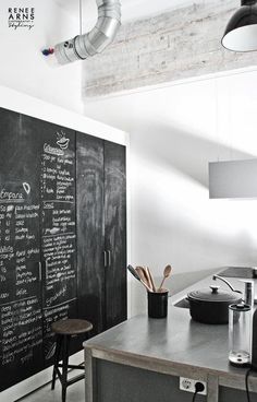 a chalkboard with writing on it is in the corner of a kitchen next to a counter