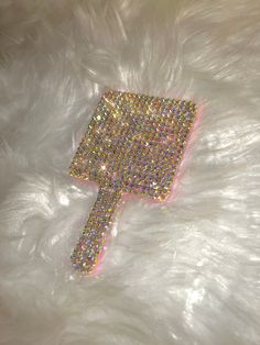 a white furry surface with a pink and gold glittered object on it's side