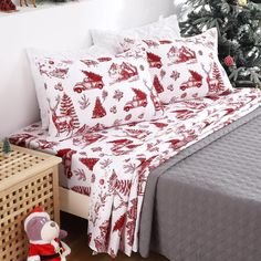 a bed covered in red and white christmas themed sheet sets next to a christmas tree