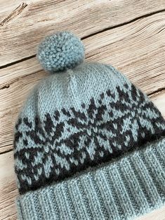 a gray and black knitted hat with a pom - pom