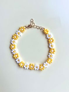 a yellow and white beaded bracelet with silver clasps on a white table top