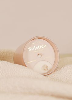 a bottle of solstice sitting on top of a white blanket with the lid open