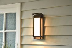 a light that is on the side of a house next to a plant and window