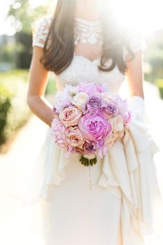 a woman in a wedding dress holding a bouquet of pink and white flowers with the sun shining behind her