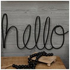 the word hello spelled with black beads on a wooden table