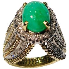 Very unique, high fashion estate ring features a bright, light apple green, variegated, oval cut jade stone, prong set and surrounded by a sparkling halo of 20 round brilliant diamonds. Elaborate side detail features 5 ropes of 14 karat yellow gold, alternating with 4 insets of 5 pave set round brilliant diamonds on both sides, which come together in an inverted "V" shape at the top and bottom of the head of the ring, and taper to the shank of the ring. Oval Jade cabochon measures 10.23 mm x 8.4 mm x 6 mm and weighs approximately 3.9 carats. 20 diamonds measure 2 mm in diameter and weigh approximately .60 carats. 40 diamonds measure 1.3 mm in diameter and weigh approximately .40 carats. Approximately 1 carat total diamond weight. Diamonds are VS in clarity and G in color. Hallmarked, "14k Luxury Lime Green Oval Rings, Luxury Emerald Ring With Oval Cabochon And 17 Jewels, Fine Jewelry Emerald Green Oval Cabochon Ring, Luxury Oval Cabochon Emerald Ring With 17 Jewels, Luxury Emerald Ring With Oval Cabochon, Exquisite Oval Green Emerald Ring, Green Oval Cabochon Emerald Ring, Exquisite Green Oval Emerald Ring, Luxury Oval Cabochon Emerald Ring