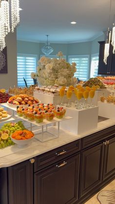 a buffet with many different types of food on it's counter top and chandelier hanging from the ceiling