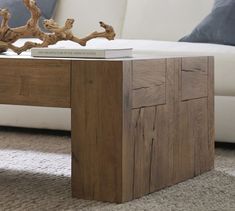 a coffee table made out of wood with a book on it's top sitting in front of a white couch