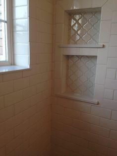 the corner of a bathroom with a window and white tile on the wall, next to a toilet