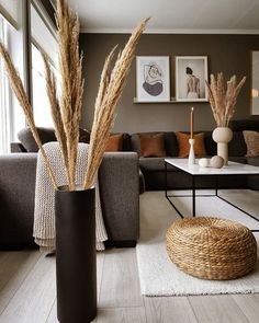 a living room filled with lots of furniture and tall grass in vases on the floor