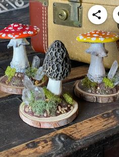 three miniature mushrooms sitting on top of a wooden table next to a suitcase and other items