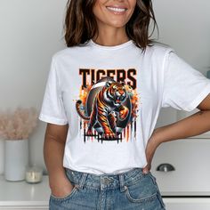 Tiger Football Tee. This tee is 100% cotton. Choose a different color from the drop-down menu. Color may vary slightly due to monitor settings.  Fit: All shirts are unisex fit, true to size, loose fit. Recommend going up 1-2 sizes for an oversized look. Please check the size chart. If you have any questions, please contact us. Please check your address to make sure it is your current address. Care Instructions:  For the best and lasting results, wash in cold water inside out. No bleach. Dry on l Cotton Sublimation Print Fan Apparel T-shirt, Fan Apparel Cotton T-shirt With Sublimation Print, Cotton Fan Apparel T-shirt With Sublimation Print, School Spirit Graphic Print Shirt For Streetwear, College Graphic Tee Shirt With Sublimation Print, School Spirit Cotton T-shirt With Screen Print, Cotton School Spirit T-shirt With Screen Print, Crew Neck T-shirt With Sublimation Print For College, Fan Apparel Cotton Shirt With Sublimation Print