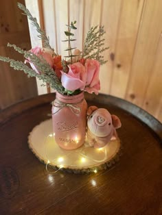 pink flowers in a mason jar with fairy lights on the side and a teddy bear sitting next to it