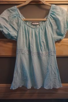 Vintage 80's princess cut boho top features a scoop neckline and puffy short elastic sleeves. Enhanced with a strip of lace trim which sits under the bust line. Shirt bottom has a scalloped design.  The light blue color is multi-tonal, meaning you will see color shading.   The material is slightly stretchy. Very feminine design. COLOR: Light Blue BRAND:  Aqua Blues Size: Medium Bust/Chest:  34" Arm Length:  2" Waist:  34" Shoulder to Bottom: 21"  Fiber Content & Care:                            100% Cotton Machine Wash Gentle  - Cold Water PLEASE OBSERVE THE MEASUREMENTS/SIZES PROVIDED ~ Thank you Additional Info: SMOKE FREE HOME  Please note: With regards to allergies ~ Please launder your item prior to wearing; I take photos outdoors and much is drifting the breeze.    Thank you ever so Color Shading, Scalloped Design, Elastic Sleeves, Festival Tops, Boho Top, Feminine Design, Light Blue Color, Blue Blouse, Boho Tops