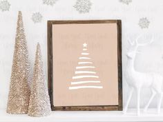 a white christmas tree sitting on top of a mantle next to two small snow covered trees