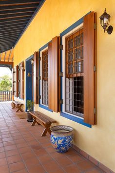 a blue and white planter sitting on the side of a yellow building with wooden windows