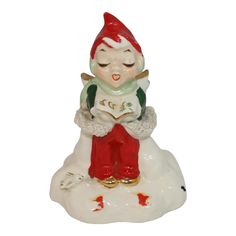 a ceramic figurine of a boy sitting on top of a snow covered ground