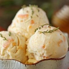 three scoops of ice cream in a white bowl with sprigs on top