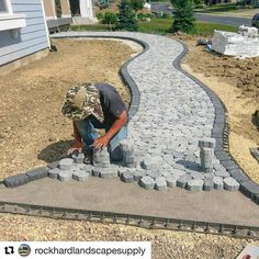 a man is working on a walkway made out of cinder blocks and cement pavers