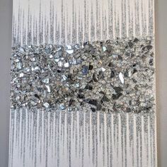 a piece of art that is made out of silver and white beads on a wall