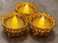 three yellow candles sitting on top of a table next to each other in glass holders