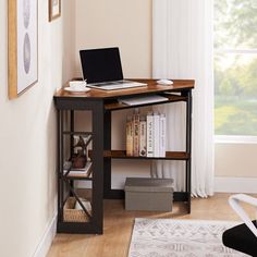 a laptop computer sitting on top of a wooden desk in front of a large window