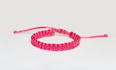 two pink string bracelets sitting on top of each other