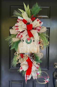 a christmas wreath on the front door with pine cones and red ribbon hanging from it