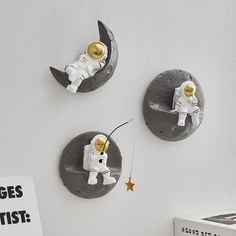 three wall clocks depicting astronauts on the moon and one with a fishing rod attached to it