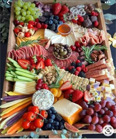 a wooden tray filled with lots of different types of cheeses and fruits on top of each other