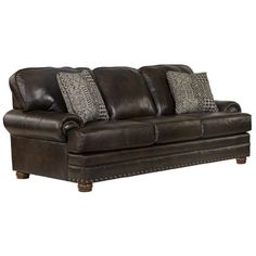 a brown leather couch with four pillows on the armrests and one pillow sitting on top of it