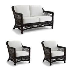 three black wicker couches with white cushions on each side and one in the middle