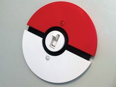 a red and white pokemon poke ball light switch plate cover on a gray wall with black trim