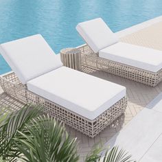 two white wicker lounge chairs next to a pool