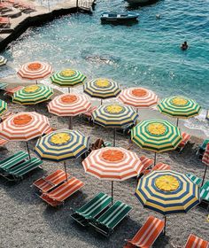 beach chairs and umbrellas are lined up on the sand near the water's edge