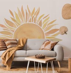 a living room with a couch, coffee table and sun wall mural on the wall