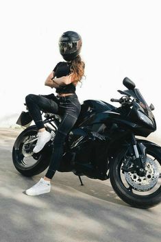 a woman sitting on top of a black motorcycle