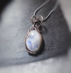 "Size: ~1.5x.5\" 20\" Sterling Chain Rainbow Moonstone a semi precious stone that promotes femininity and protection A milky white stone that flashes different colors in the light This pendant is intricately twisted and woven with pure silver wire and a natural rainbow moonstone. Each of my Pendants are unique pieces of wearable art, no two are ever exactly alike. I recommend keeping it safe from direct water or chemical exposure (sun tan spray, perfume, etc) I pride myself on making beautiful and magical artisan crafts. Each piece is delicately worked by my own hands in my home studio, using high quality and genuine materials. All gemstones used in my pieces are naturally colored and authentic, NEVER glass or plastic (unless specified)." White Gemstone Jewelry For Gifts, Minimalist Moonstone Jewelry For Healing, White Gemstone Pendant Jewelry, Bohemian Moonstone Round Pendant Jewelry, Mystical Moonstone Jewelry With Large Stone, Minimalist White Moonstone Jewelry, White Moonstone Jewelry With Moon Charm, White Necklace With Moon Charm For Healing, Handmade Minimalist Moonstone Necklace