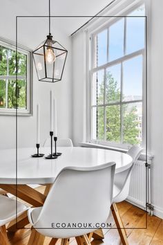 a white dining room table with chairs and a lantern hanging from the ceiling over it