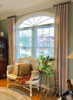 a living room filled with furniture next to a window covered in curtains and drapes