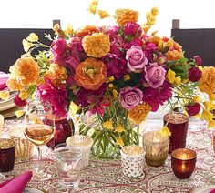 a vase filled with lots of colorful flowers on top of a dining room table covered in pink and yellow napkins