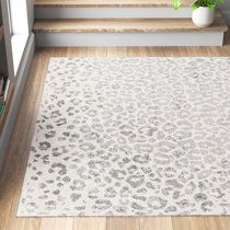 a leopard print rug is on the floor next to some stairs and a potted plant