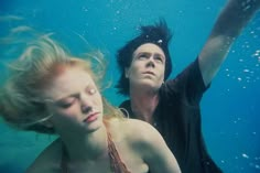 a man and woman are underwater in the blue water with their hair blowing in the wind